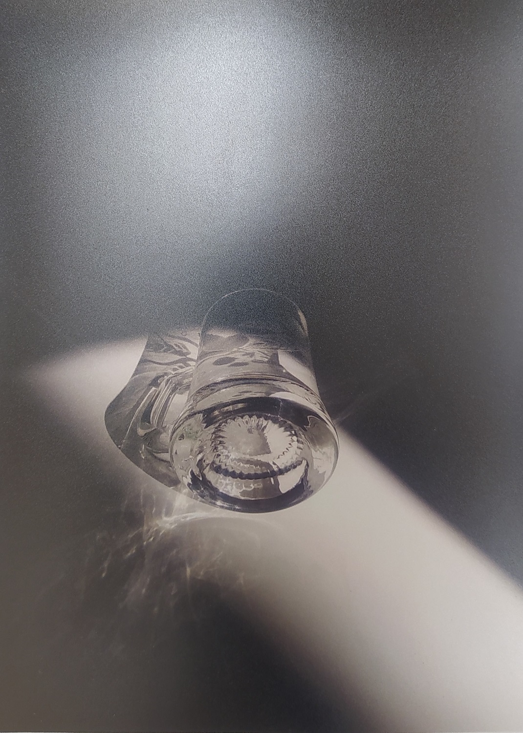 Czarno-białe zdjęcie przedstawiające leżący, szklany kieliszek.