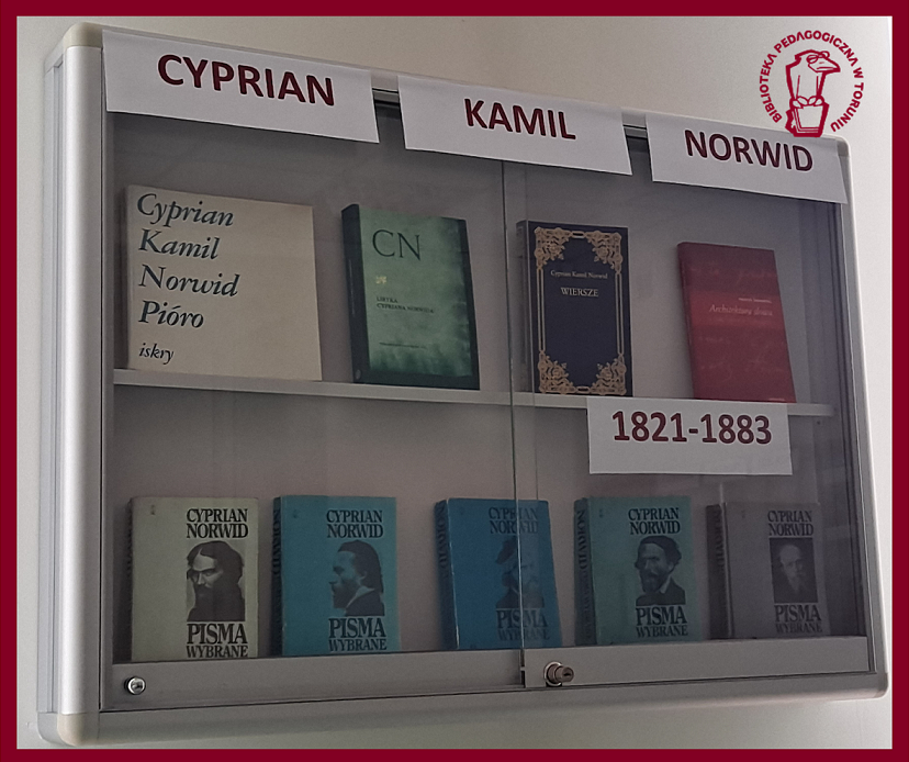 Na zdjęciu widać gablotę, w której znajdują się książki. U góry widoczny jest napis CYPRIAN KAMIL NORWID. niżej widzimy lata życia pisarza 1821-1883. W prawym górnym rogu znajduje się logo biblioteki