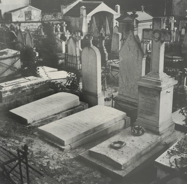 Czarno-białe zdjęcie przedstawiające cmentarz. Na pierwsdzym planie trzy groby widziane od przodu z ukosa. Środkowy grób to miejsce pochówku Norwida.