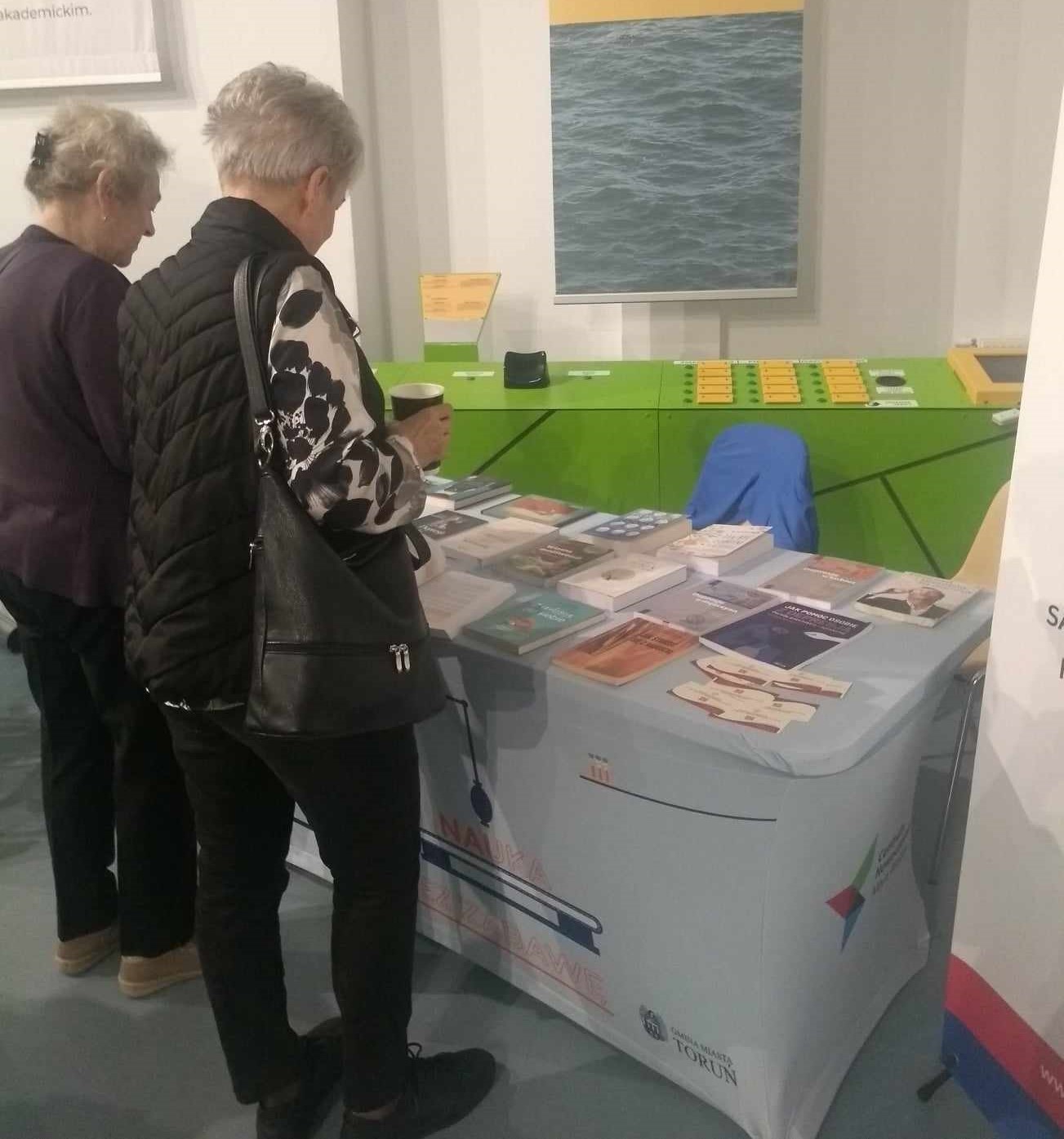 Dwie kobiety przeglądają książki leżące na stole
