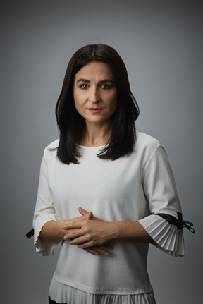 Kobieta z&nbsp;ciemnymi włosami, w&nbsp;białej bluzce, zdjęcie do&nbsp;pasa.